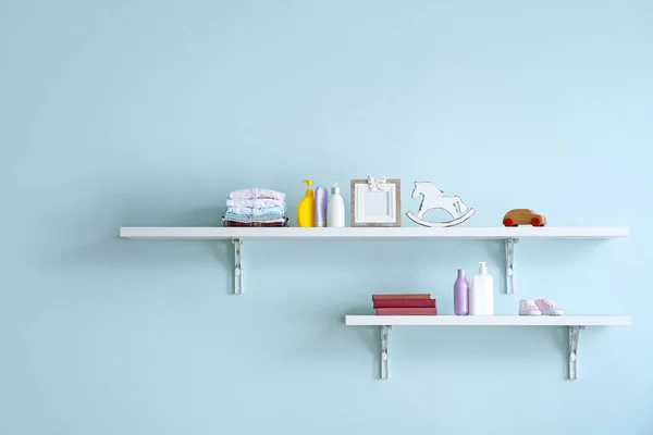 Shelves with baby accessories on color wall — 스톡 사진