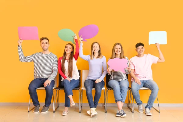 Groep jongeren met lege spraakbellen in de buurt van kleurenmuur — Stockfoto
