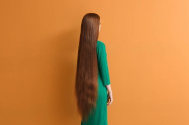 Young woman with beautiful long hair on color background