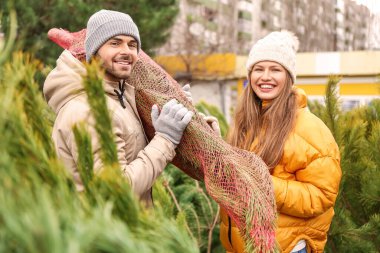Genç çift marketten Noel ağacı alıyor.