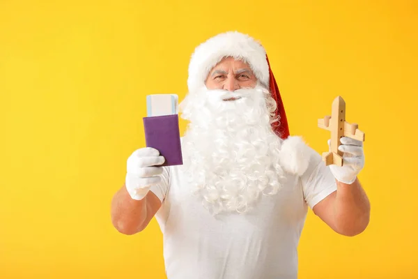 Santa Claus s dokumenty a hračka letadlo na barevném pozadí. Koncept dovolené — Stock fotografie