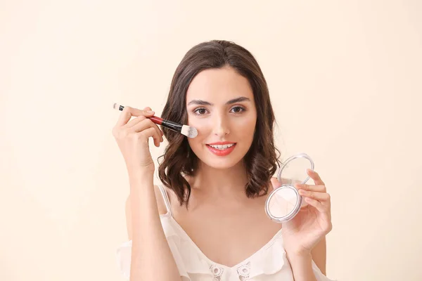 Krásná mladá žena, která používá make-up na pozadí — Stock fotografie