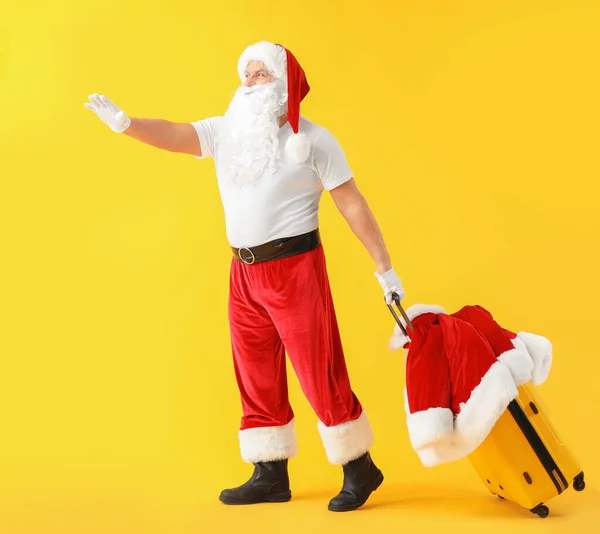 Santa Claus se zavazadly na barevném pozadí. Koncept dovolené — Stock fotografie