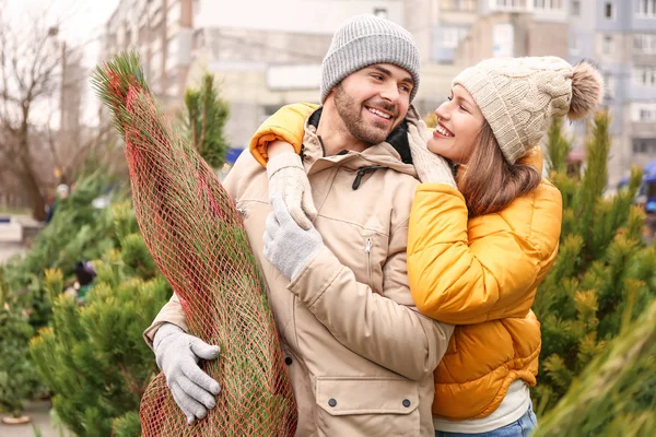Casal jovem comprando árvore de Natal no mercado — Fotografia de Stock