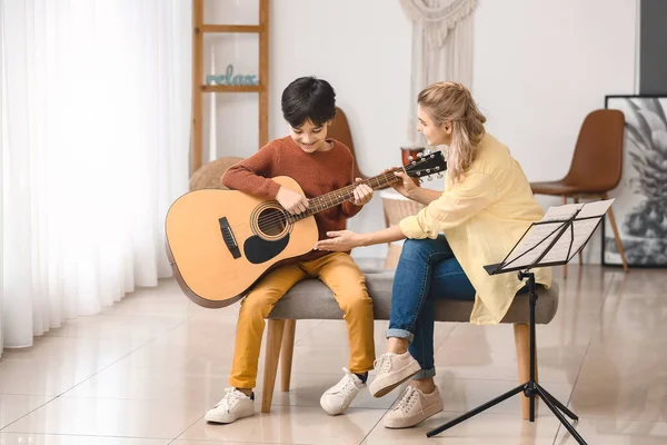 Profesora de música privada dando clases de guitarra a un niño en casa — Foto de Stock