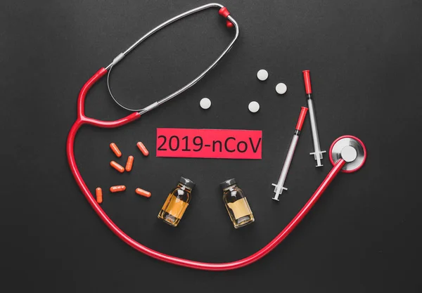 Стетоскоп і ліки для коронавірусу на темному тлі — стокове фото
