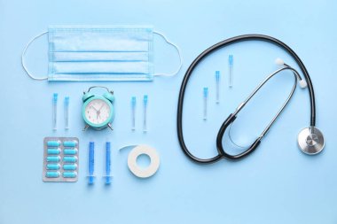 Set of medical supplies with alarm clock on color background