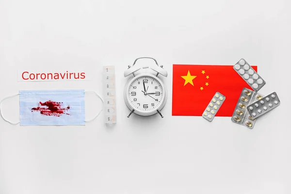 National flag of China, alarm clock, protective mask with blood and medicines for Coronavirus on white background
