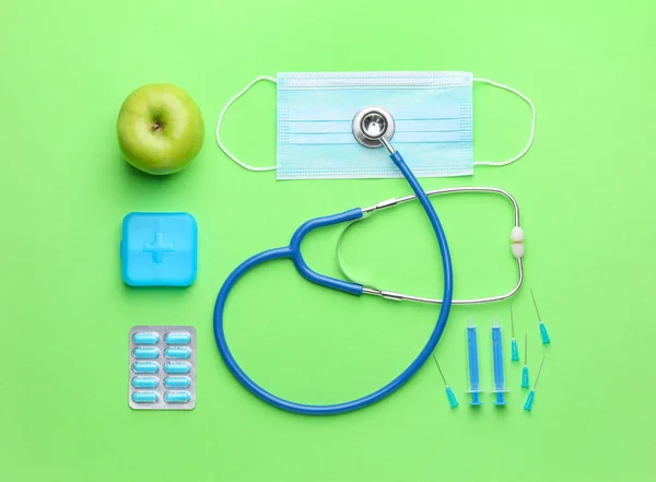 Set of medical supplies with apple on color background — Stock Photo, Image