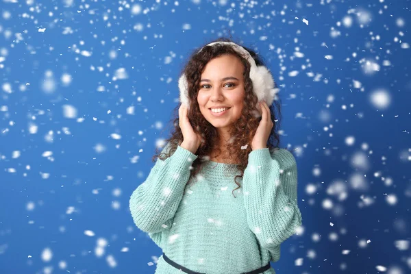 Giovane donna afro-americana in maglione caldo e neve caduta su sfondo di colore — Foto Stock