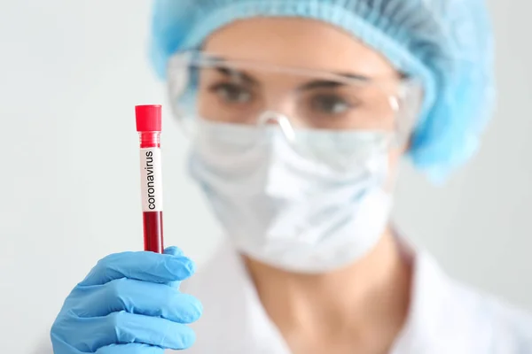 Female doctor holding blood sample in test tube with text CORONAVIRUS, closeup — Stock Photo, Image