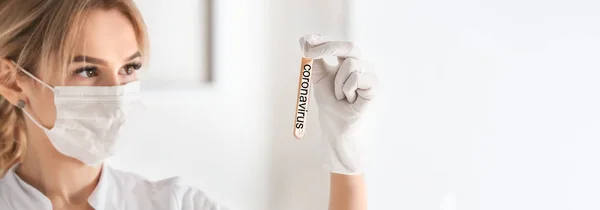 Female doctor holding test tube with text CORONAVIRUS in laboratory — Stock Photo, Image