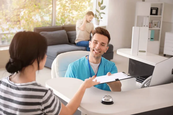 Male receptionist working with patient in clinic — Stock Photo, Image