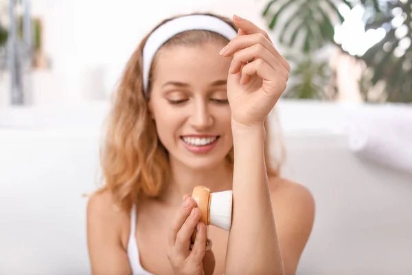 Beautiful young woman with massage brush in bathroom — Stock Photo, Image