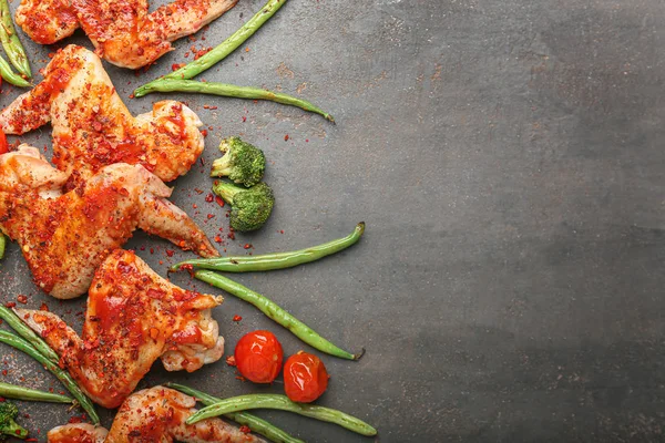 Cooked chicken wings with vegetables on dark background
