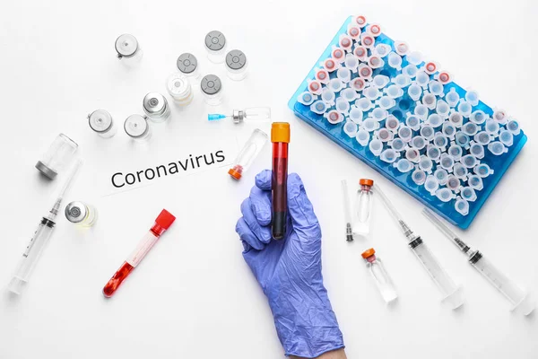 Mano del médico con muestra de sangre y vacuna para el Coronavirus sobre fondo blanco — Foto de Stock