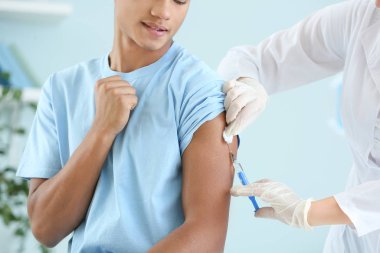 Klinikte genç bir çocuğu aşılayan doktor.