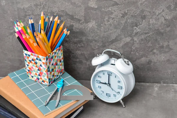 Zestaw materiałów szkolnych i zegar na stole — Zdjęcie stockowe