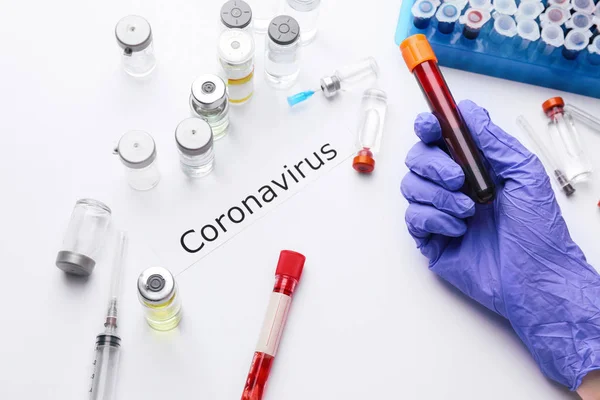 Mano del médico con muestra de sangre y vacuna para el Coronavirus sobre fondo blanco — Foto de Stock