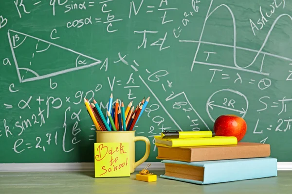 Set perlengkapan sekolah dan apel di meja dekat papan tulis — Stok Foto