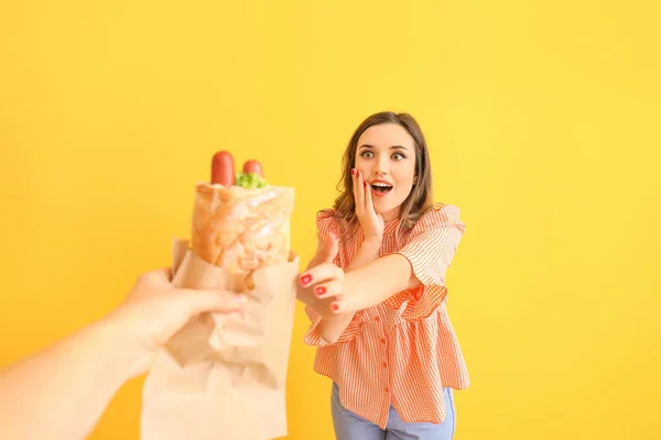 Heyecanlı genç bir kadın renkli arka planda Fransız sosislisi için elini uzatıyor. — Stok fotoğraf