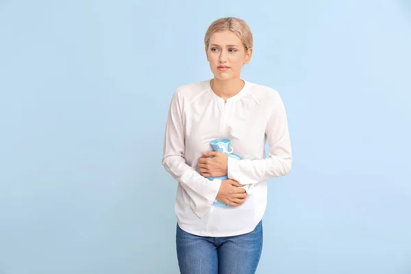 Young woman suffering from menstrual cramps on color background — ストック写真