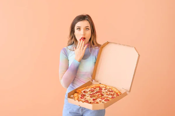 Portrait of surprised young woman with pizza on color background — Stock Photo, Image