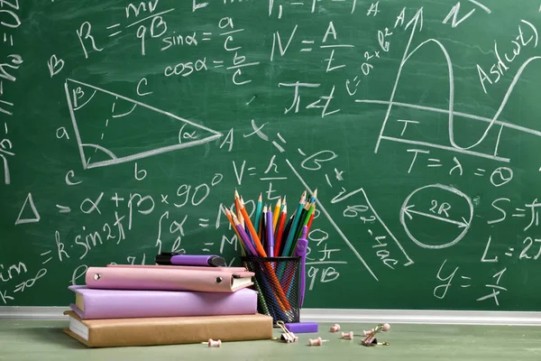 Ensemble de fournitures scolaires sur la table près du tableau noir — Photo