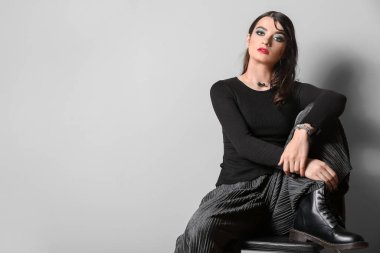 Güzel, şık bir kadın, arka planda, sandalyede oturuyor.