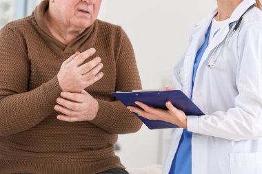 Klinikte Parkinson sendromu olan yaşlı bir adamla çalışan kadın doktor.