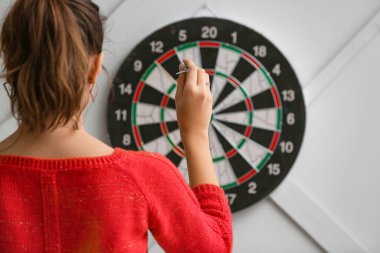 Genç bayan içeride dart oynuyor.