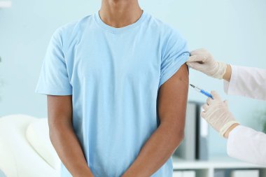 Klinikte genç bir çocuğu aşılayan doktor.