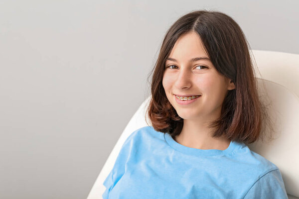 Teenage girl with dental braces sitting in dentist's armchair