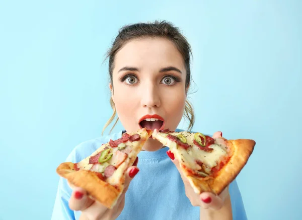 Portrait of beautiful young woman eating tasty pizza on color background — Stock Photo, Image