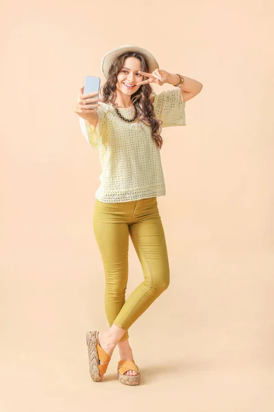 Jeune femme prenant selfie sur fond de couleur — Photo