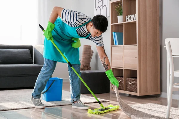 Joven asiático hombre limpieza piso en casa — Foto de Stock