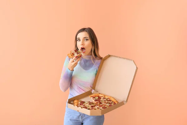 Portrait of beautiful young woman eating pizza on color background — Stock Photo, Image