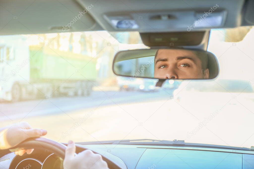 Reflection of driver in car rear view mirror