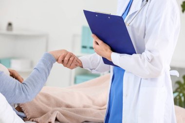 Klinikte Parkinson sendromu olan yaşlı bir kadınla çalışan kadın doktor.