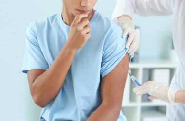 Klinikte genç bir çocuğu aşılayan doktor.