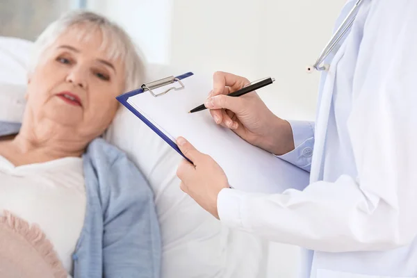 Γυναίκα γιατρός που εργάζεται με ηλικιωμένη γυναίκα που πάσχει από το σύνδρομο Parkinson στην κλινική — Φωτογραφία Αρχείου