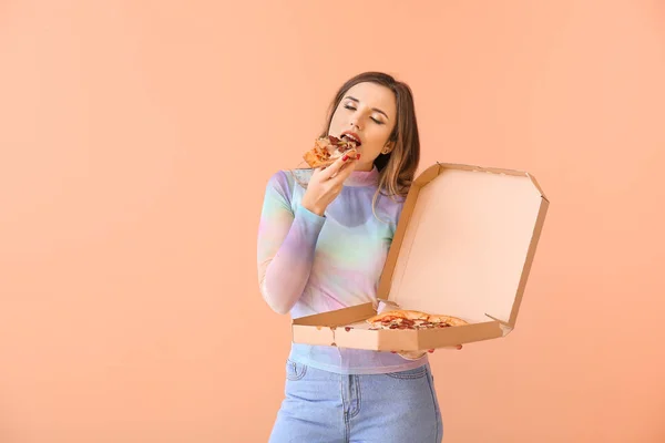 Portrait of beautiful young woman eating pizza on color background — Stock Photo, Image
