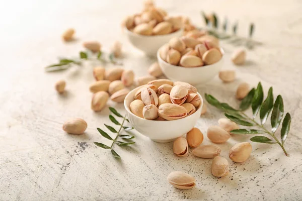 Bowls with tasty pistachio nuts on light background — Stock Photo, Image