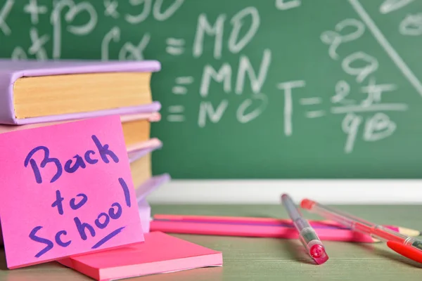 Conjunto de útiles escolares en la mesa cerca de pizarra, primer plano — Foto de Stock