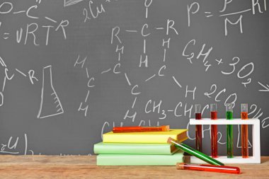 Okul malzemeleri ve test tüpleri karatahtanın yanındaki masada.