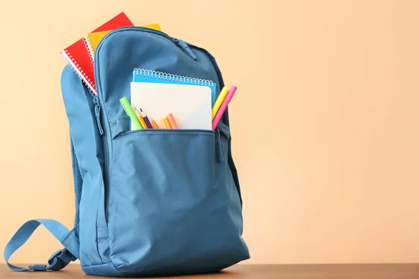 School backpack with stationery on color background — Stock Photo, Image