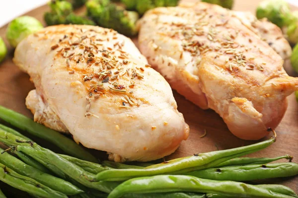 Cooked chicken fillet with vegetables on board