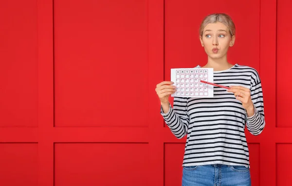 Jonge vrouw met kalender op kleur achtergrond. Menstruatieconcept — Stockfoto
