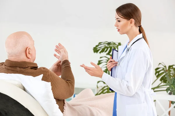 Medico donna che lavora con uomo anziano affetto da sindrome di Parkinson in clinica — Foto Stock