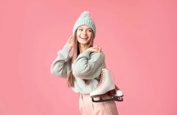 Mooie jonge vrouw met schaatsen op kleur achtergrond — Stockfoto